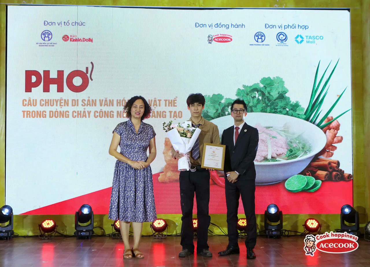 Bà Phạm Thị Thanh Hường - Trưởng ban Khoa học văn hóa (Văn phòng UNESCO tại Việt Nam) và ông Yokoyama Hiroya - Phó Giám đốc khối Marketing Công ty Cổ phần Acecook Việt Nam trao giải thưởng cho thí sinh Nguyễn Quang Minh đạt giải Nhất cuộc thi “Ký họa về di sản văn hóa phi vật thể Phở