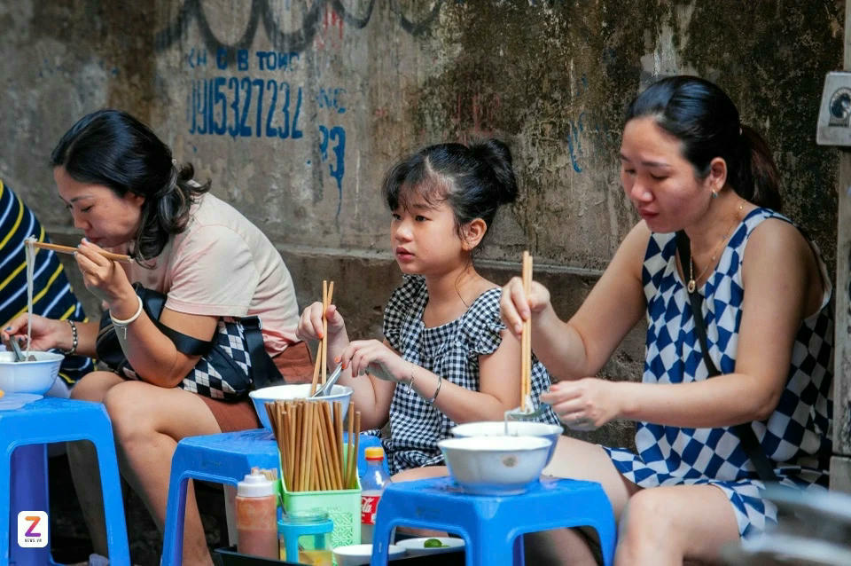 Thực khách tự xếp ghế nhựa, bê phở và ngồi ăn ngoài vỉa hè hoặc ở quán cà phê bên cạnh trên phố Ấu Triệu. Ảnh: Thụy Trang.